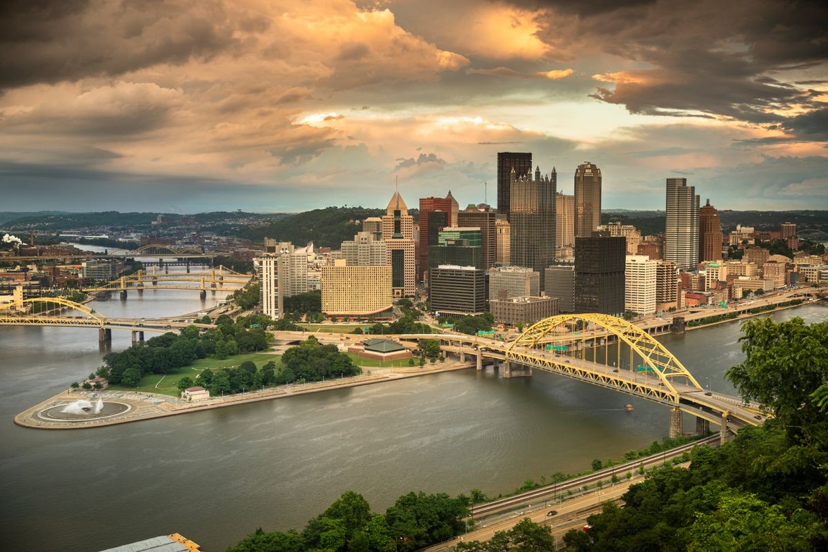 Dramatic skyline of Pittsburgh under a stormy sky, adjacent to the PittsburghLuxe affordable housing project featuring 26 eco-friendly homes, promoting sustainable urban development by Luxe Living Homes.